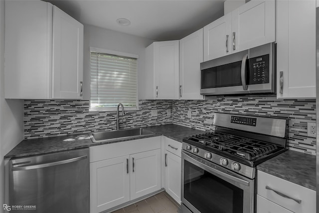 kitchen with a sink, tasteful backsplash, appliances with stainless steel finishes, and dark countertops