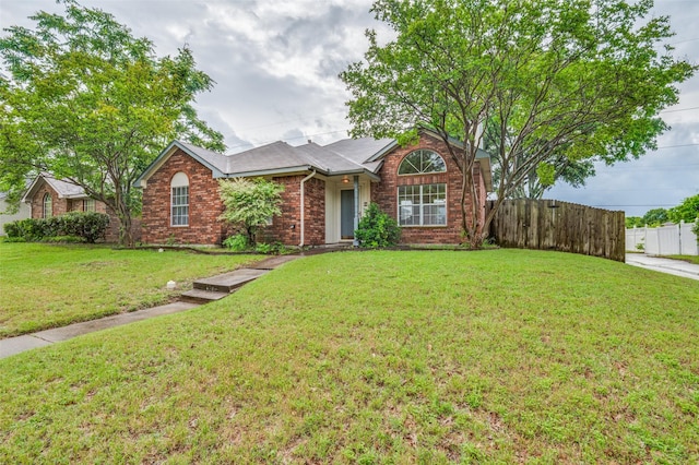 ranch-style home with brick siding, a front lawn, and fence