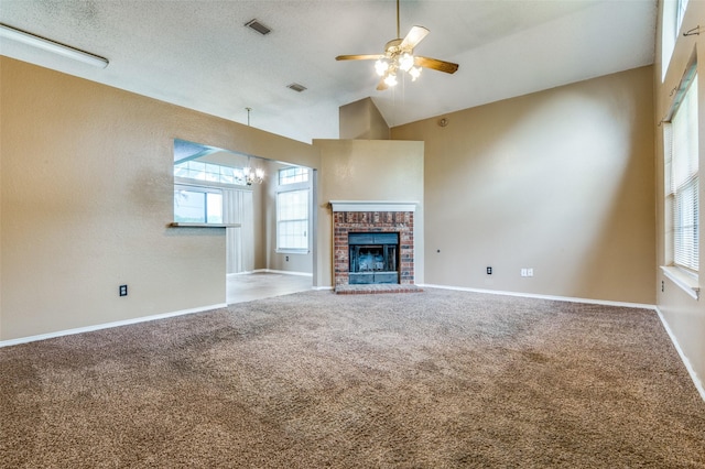 unfurnished living room featuring ceiling fan with notable chandelier, a wealth of natural light, carpet floors, and lofted ceiling