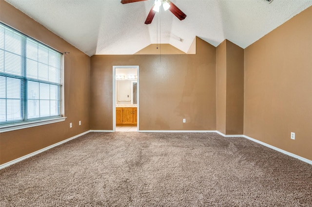 empty room featuring lofted ceiling, a textured ceiling, baseboards, light carpet, and a ceiling fan