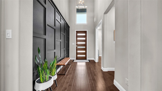 foyer featuring baseboards, a high ceiling, and dark wood-style floors