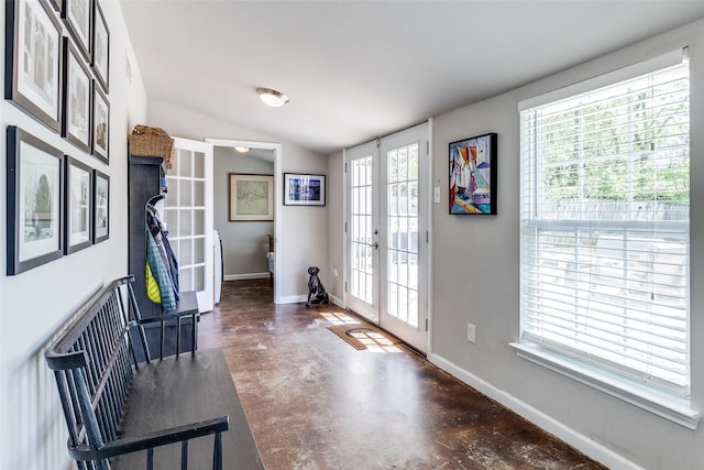 foyer with french doors, baseboards, finished concrete floors, and vaulted ceiling