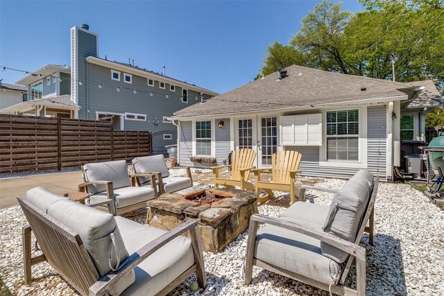 back of house with an outdoor living space with a fire pit, a chimney, fence, french doors, and roof with shingles