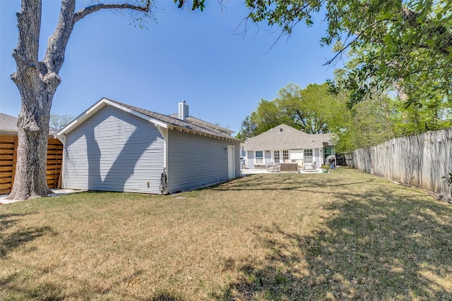 back of property featuring a yard, a fenced backyard, a chimney, and a patio area