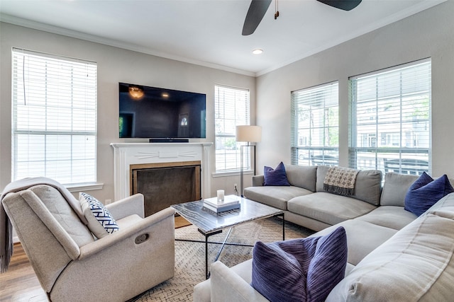 living room with recessed lighting, a fireplace, crown molding, a ceiling fan, and light wood-style floors