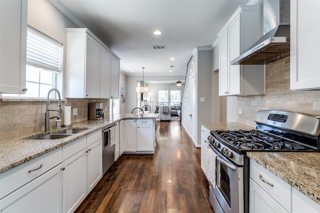 kitchen with visible vents, a sink, wall chimney range hood, a peninsula, and stainless steel appliances