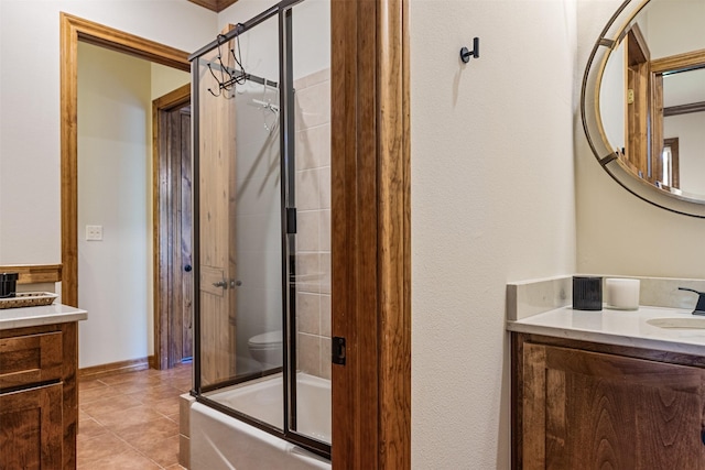 bathroom with vanity, tile patterned flooring, toilet, combined bath / shower with glass door, and baseboards