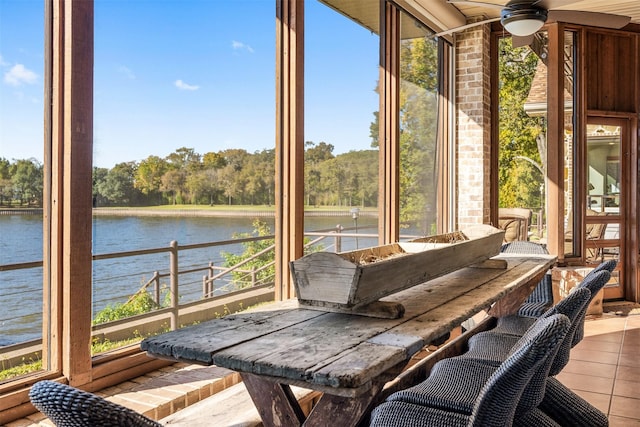 sunroom / solarium with ceiling fan and a water view