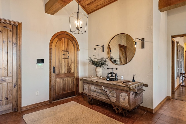 foyer featuring baseboards, an inviting chandelier, beamed ceiling, tile patterned floors, and high vaulted ceiling