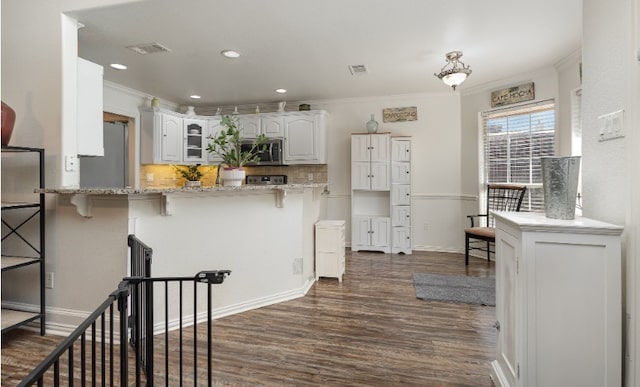 kitchen with glass insert cabinets, a kitchen bar, dark wood finished floors, crown molding, and stainless steel appliances