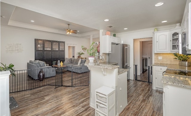 kitchen with white cabinets, washing machine and clothes dryer, a raised ceiling, and a peninsula