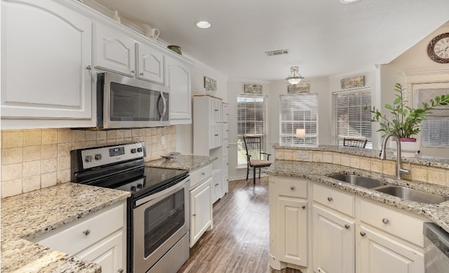 kitchen featuring tasteful backsplash, visible vents, appliances with stainless steel finishes, wood finished floors, and a sink