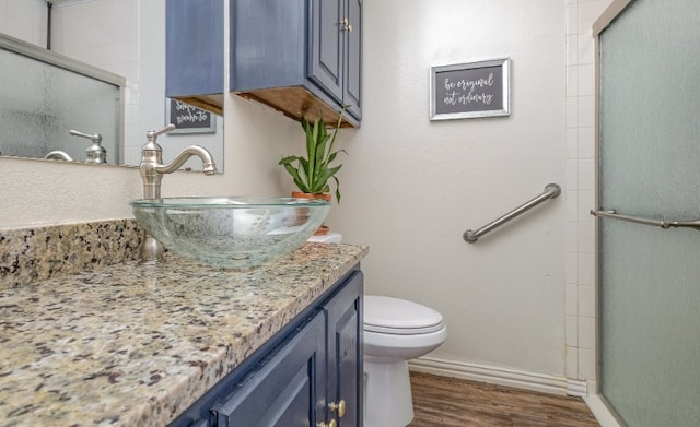 bathroom with baseboards, toilet, an enclosed shower, vanity, and wood finished floors