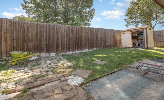 view of yard with a shed, a fenced backyard, and an outbuilding