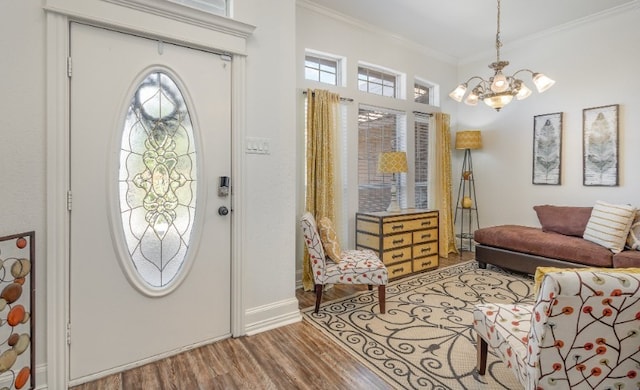 entrance foyer with crown molding, wood finished floors, a notable chandelier, and plenty of natural light