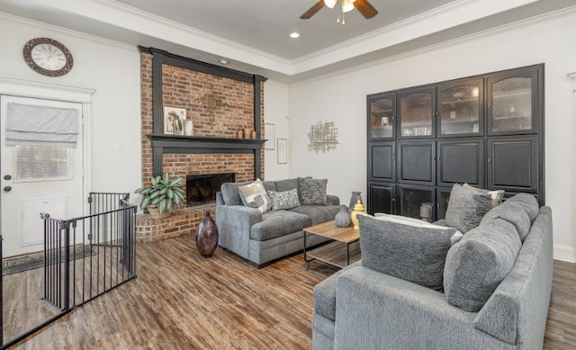 living room with crown molding, ceiling fan, a fireplace, recessed lighting, and wood finished floors