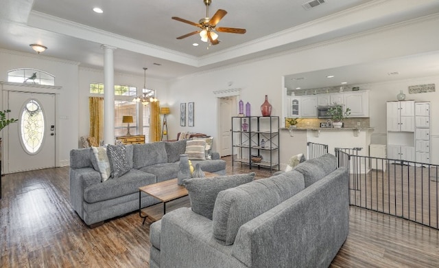 living room with a tray ceiling, crown molding, ceiling fan with notable chandelier, and wood finished floors