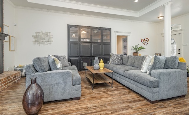 living area with crown molding, a tray ceiling, ornate columns, and wood finished floors