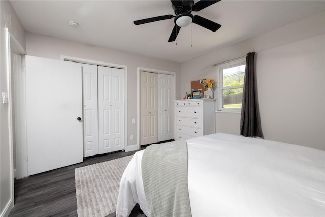 bedroom featuring a ceiling fan, dark wood-style floors, and multiple closets