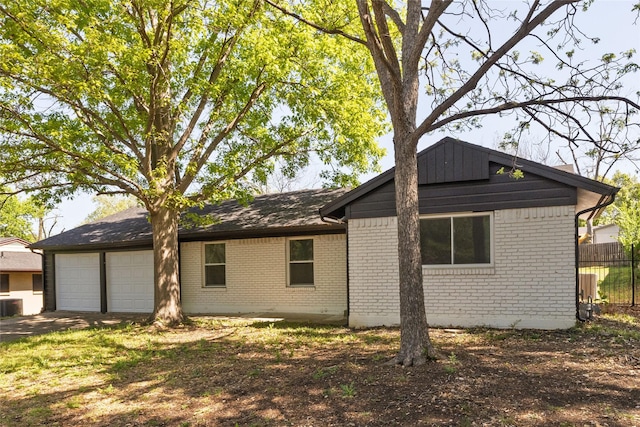 view of property exterior with an attached garage, concrete driveway, fence, central air condition unit, and brick siding