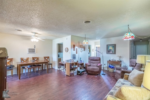 living room featuring a textured ceiling, visible vents, baseboards, a ceiling fan, and wood finished floors