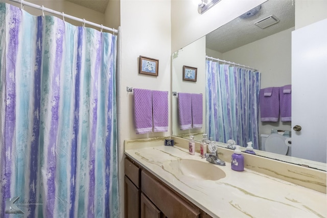 full bathroom featuring a shower with shower curtain, a textured ceiling, toilet, and vanity