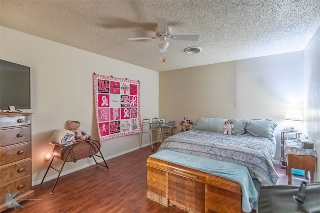 bedroom featuring wood finished floors, a textured ceiling, ceiling fan, baseboards, and visible vents