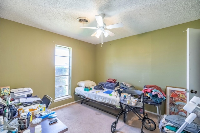 carpeted bedroom featuring a textured ceiling, baseboards, ceiling fan, and visible vents