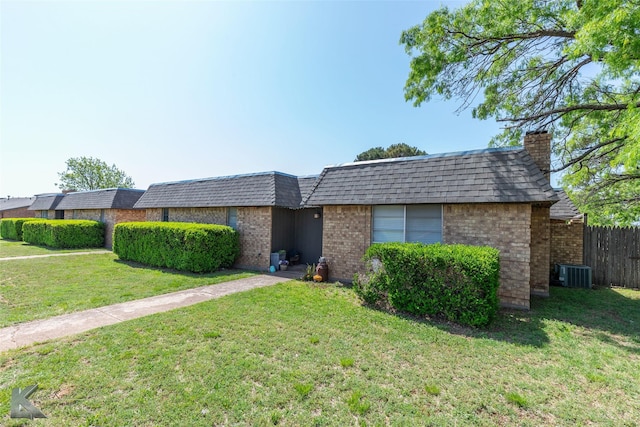 view of front of home featuring mansard roof, brick siding, a front yard, and cooling unit