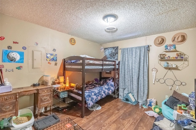 bedroom featuring wood finished floors, a textured ceiling, and visible vents