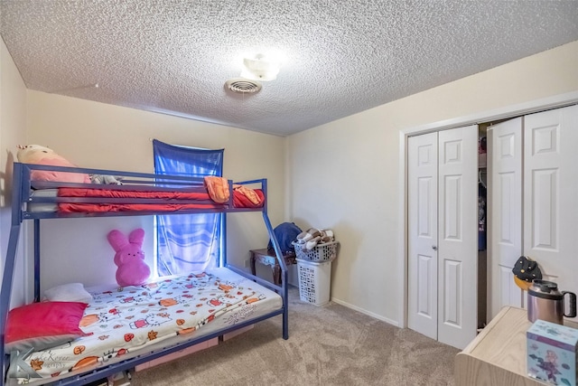 bedroom with a textured ceiling, a closet, carpet flooring, and visible vents