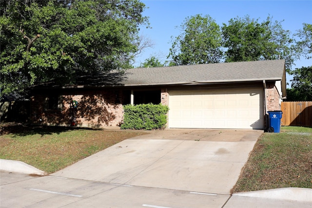 ranch-style home with brick siding, fence, a garage, a front lawn, and concrete driveway