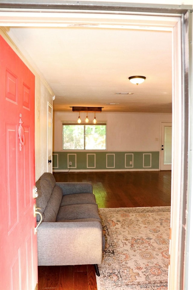 living area featuring visible vents, ornamental molding, and wood-type flooring