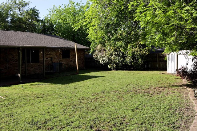 view of yard featuring fence, a storage unit, cooling unit, and an outbuilding
