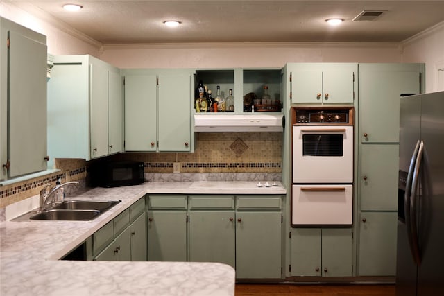 kitchen with crown molding, a sink, under cabinet range hood, and white appliances