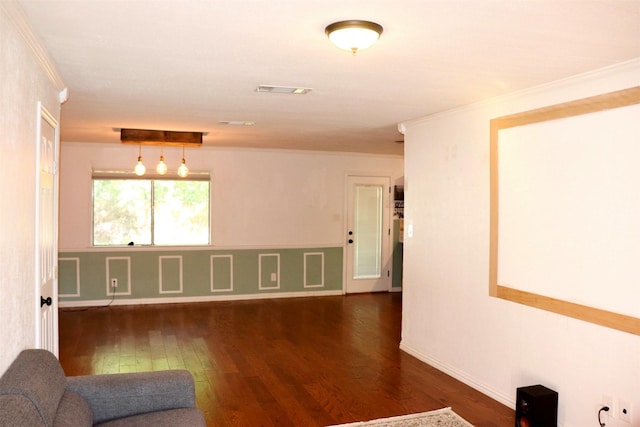 empty room with dark wood-style floors, visible vents, crown molding, and baseboards
