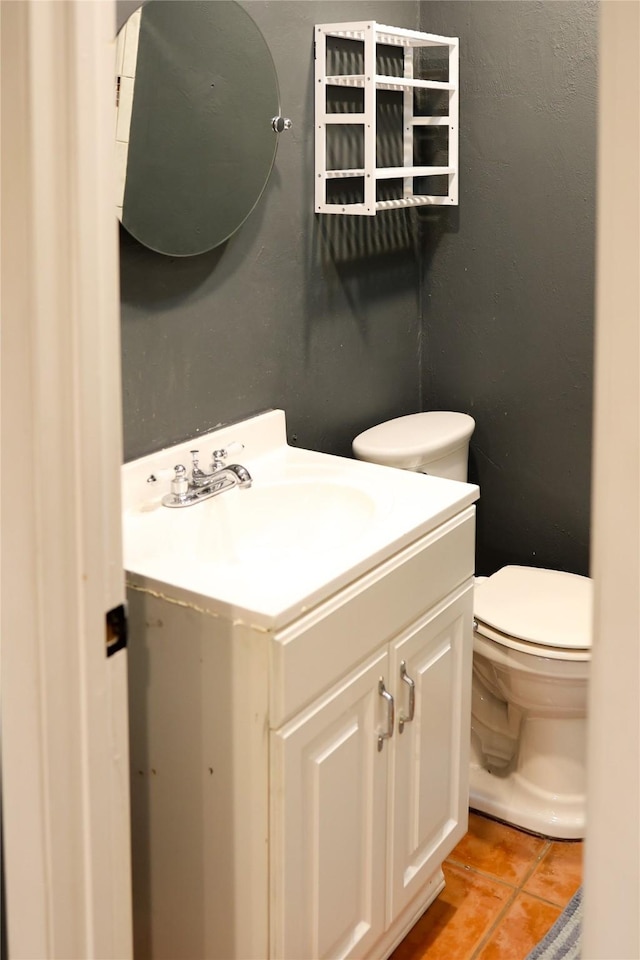 half bath with toilet, tile patterned flooring, and vanity