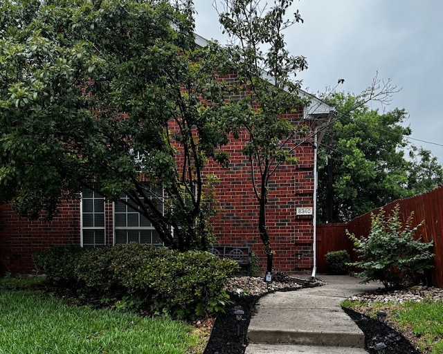 view of property exterior with brick siding and fence