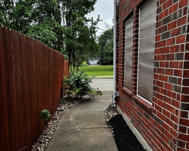 view of side of property with brick siding and fence