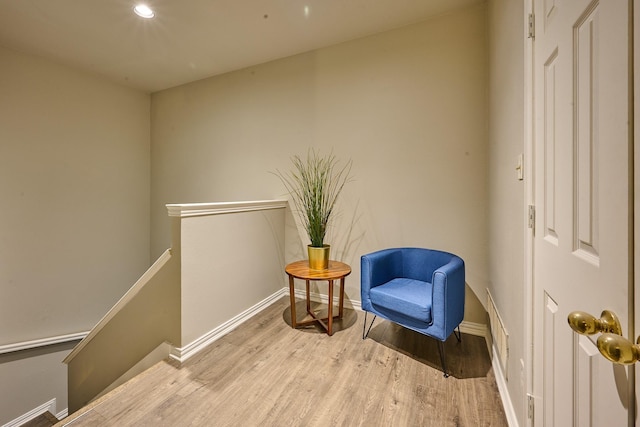 sitting room featuring visible vents, wood finished floors, baseboards, recessed lighting, and an upstairs landing
