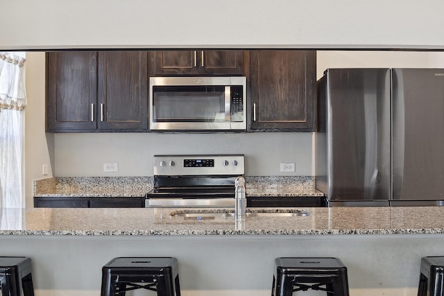 4538 Cherbourg St, Dallas, TX 75216 - kitchen featuring stainless steel appliances, dark brown cabinetry, and a breakfast bar