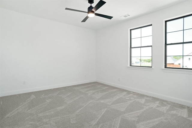 spare room featuring visible vents, ceiling fan, light colored carpet, and a healthy amount of sunlight