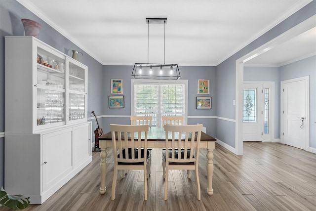 dining room with baseboards, wood finished floors, and ornamental molding