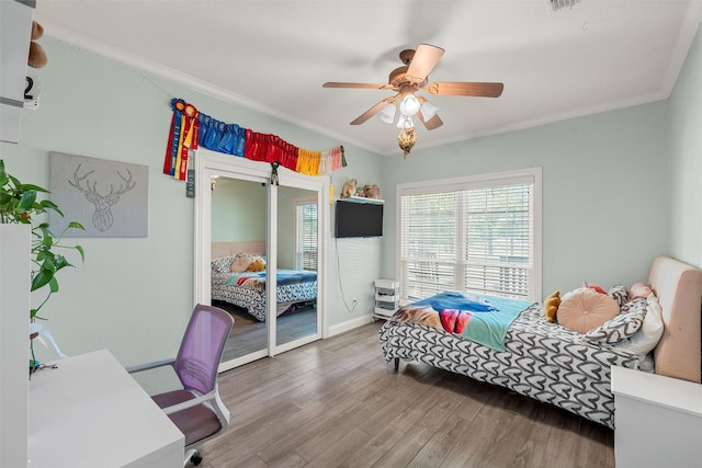 bedroom with wood finished floors, visible vents, a ceiling fan, ornamental molding, and baseboards