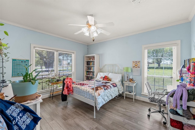 bedroom featuring multiple windows, wood finished floors, and ornamental molding