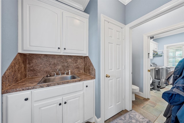 bathroom with backsplash, vanity, washing machine and dryer, toilet, and stone finish floor