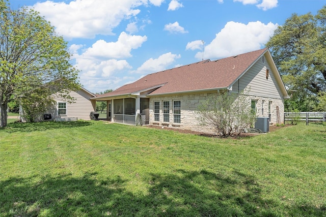 back of house with fence, cooling unit, stone siding, a lawn, and a sunroom