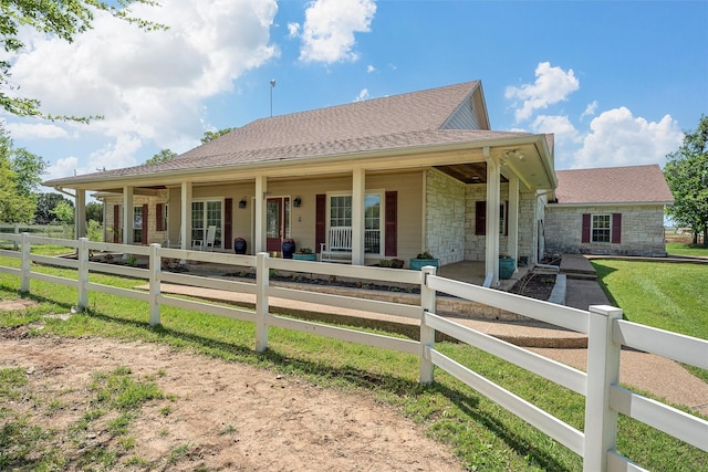 back of property featuring stone siding, covered porch, and a fenced front yard