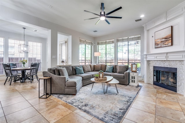 living room with a fireplace, visible vents, ceiling fan with notable chandelier, and light tile patterned flooring