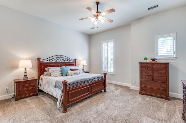 bedroom featuring visible vents, baseboards, multiple windows, and light carpet